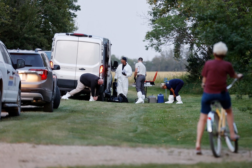 A forensics team by the side of the road at stabbing site, young boy on a bike in the foreground