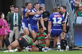 A Bulldogs NRL player yells in celebration as he is hugged from behind by a teammate after a try.