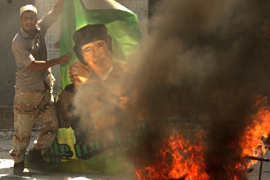 Rebel burns poster of Gaddafi