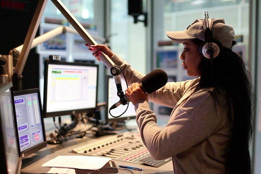 A young woman adjusting a microphone in a recording studio