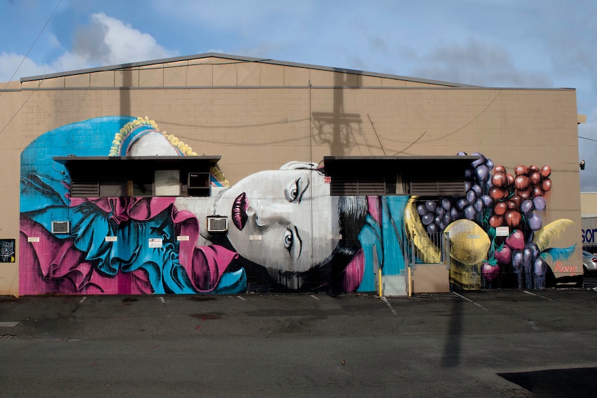 A mural of a woman in a wall in Hawaii with many protrusions.