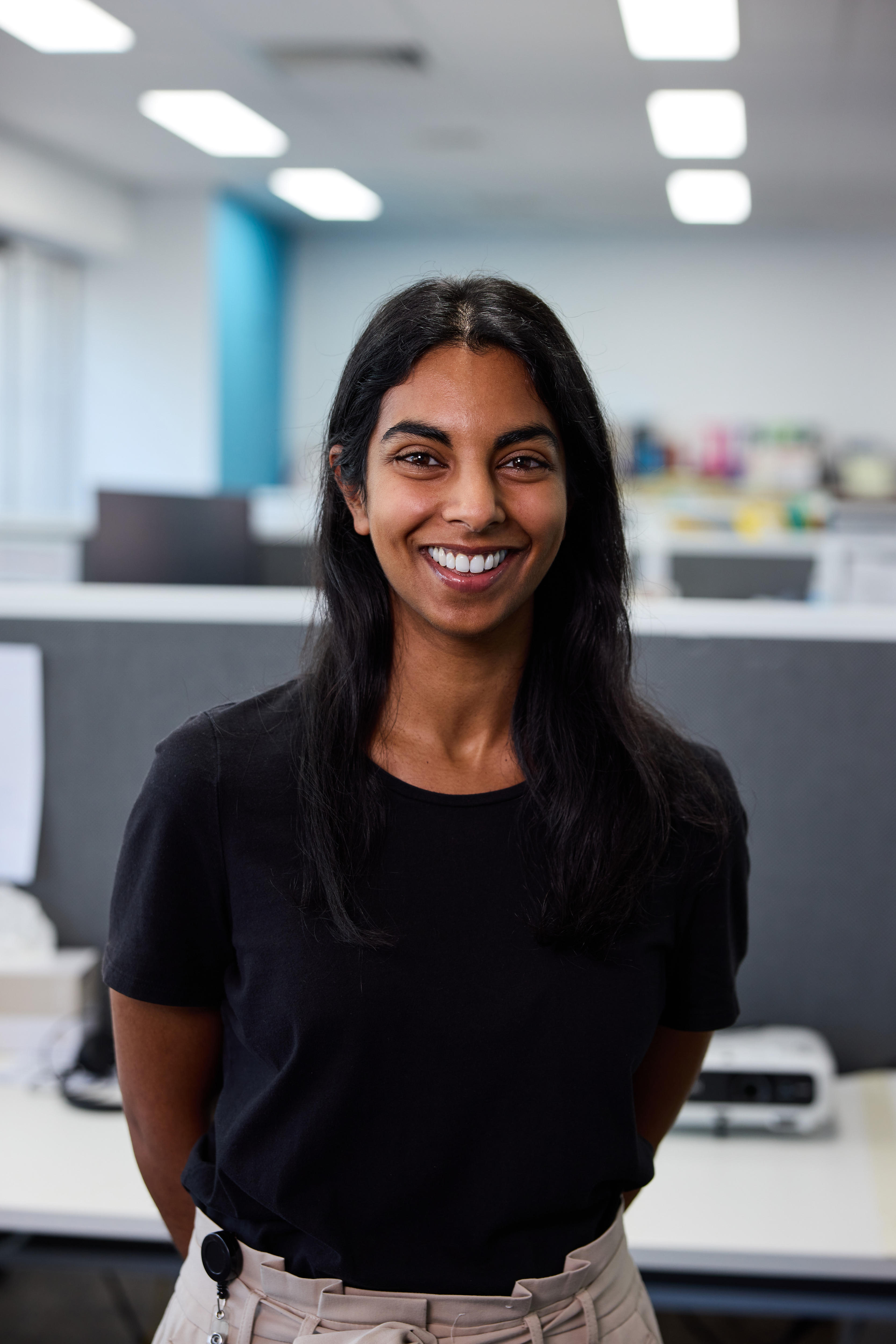 A woman smiles standing in an office.