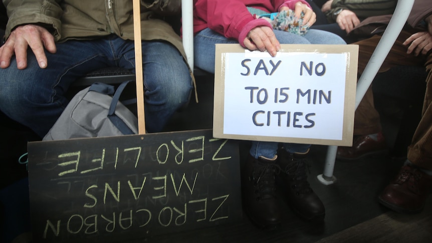 A person on a bus holding a sign that says 'say no to 15 min cities'