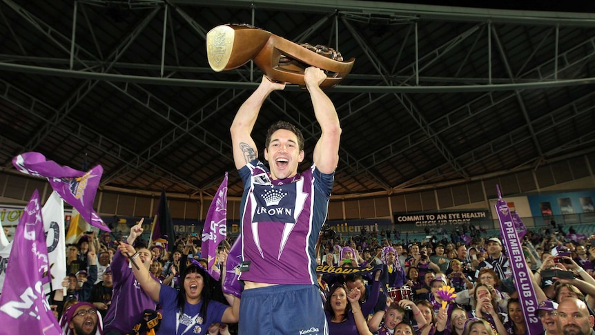 Melbourne Storm player Billy Slater lifts the NRL premiership trophy in front of fans after the 2012 grand final.