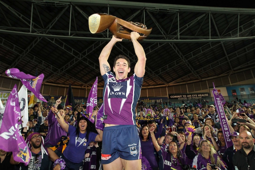 Melbourne Storm player Billy Slater lifts the NRL premiership trophy in front of fans after the 2012 grand final.