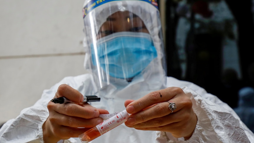 Un trabajador de la salud etiqueta un tubo de muestra de ensayo durante el brote de coronavirus en Hanoi
