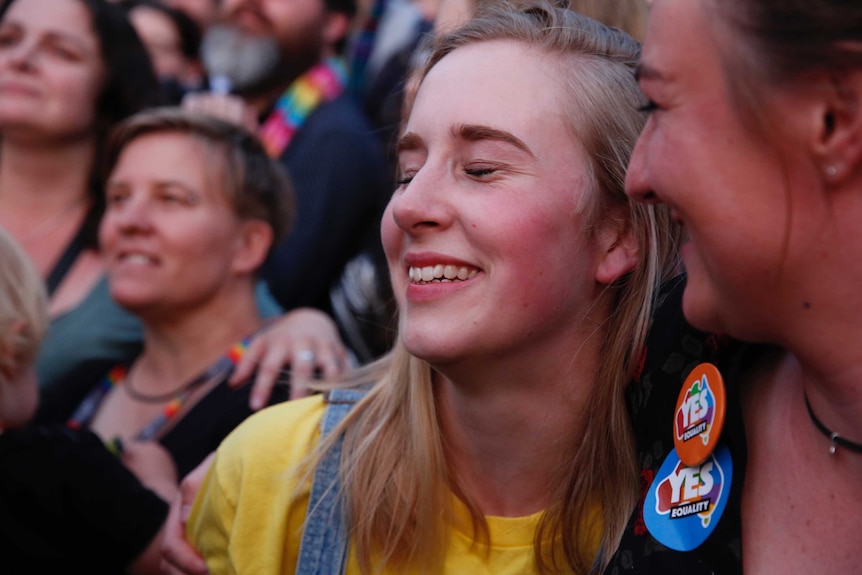 A woman smiles with her eyes closed, among a crowd of Yes supporters.