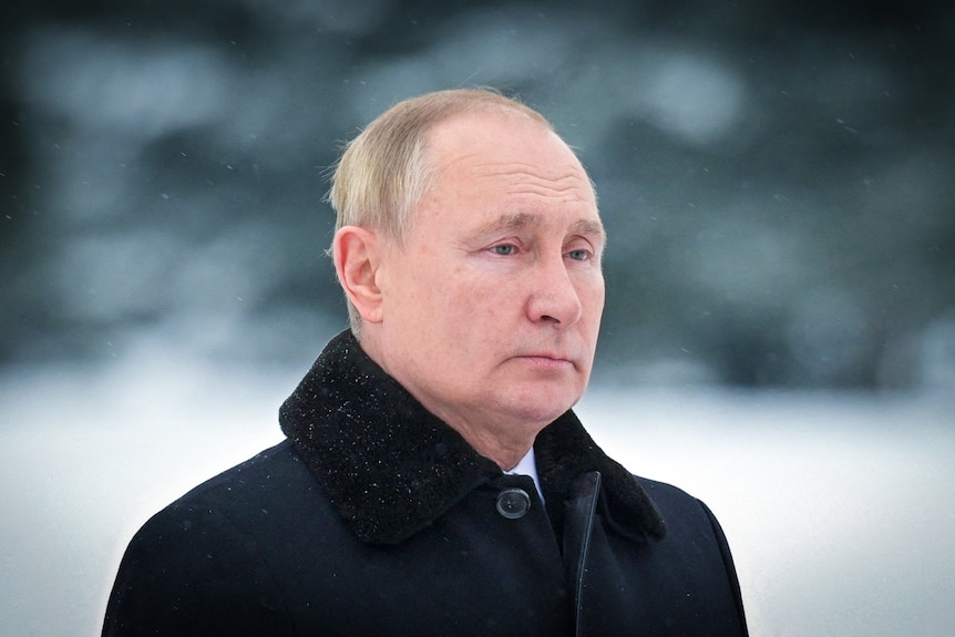 Władimir Putin wygląda ponuro w czarnym płaszczu stojąc na śniegu 