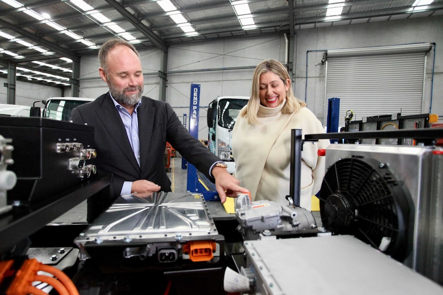 Tony Fairweather and Danielle Wallace looking at an electric motor under the hood of a car.