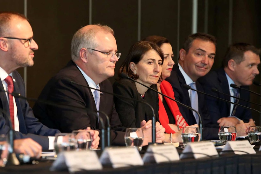 Scott Morrison sits at a panel table. To his left is Gladys Berejiklian, and to his right is Andrew Barr