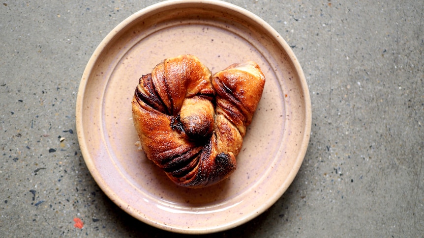 A sourdough Swedish knot on a plate, filled with chocolate and cinnamon, a fun baking project for breakfast or snacks.