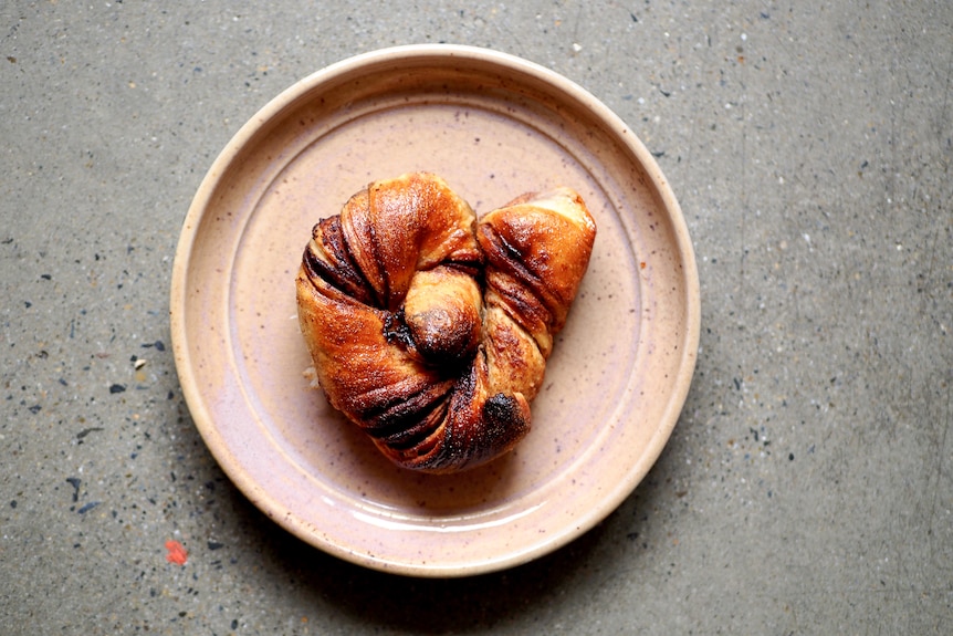 A sourdough Swedish knot on a plate, filled with chocolate and cinnamon, a fun baking project for breakfast or snacks.