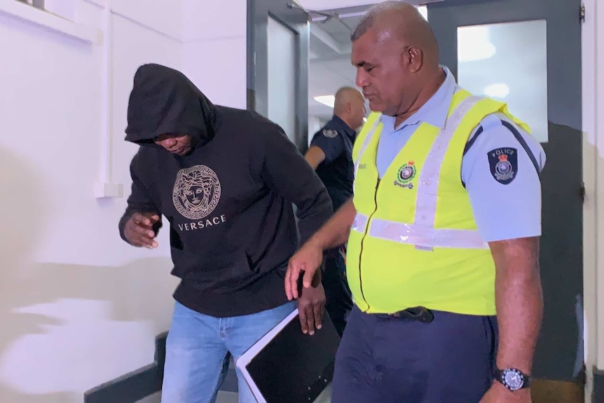 Murder suspect Henri Lusaka is led into court by a Fiji police officer.