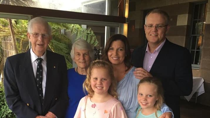 The Morrison family stands together under a verandah