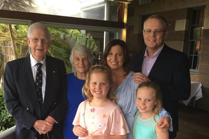 The Morrison family stands together under a verandah
