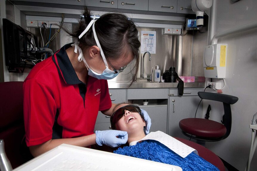 A dentist treats a child in a surgery.