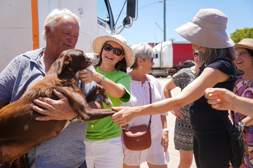 Barry holds Floss, as a few people surround and greet them 