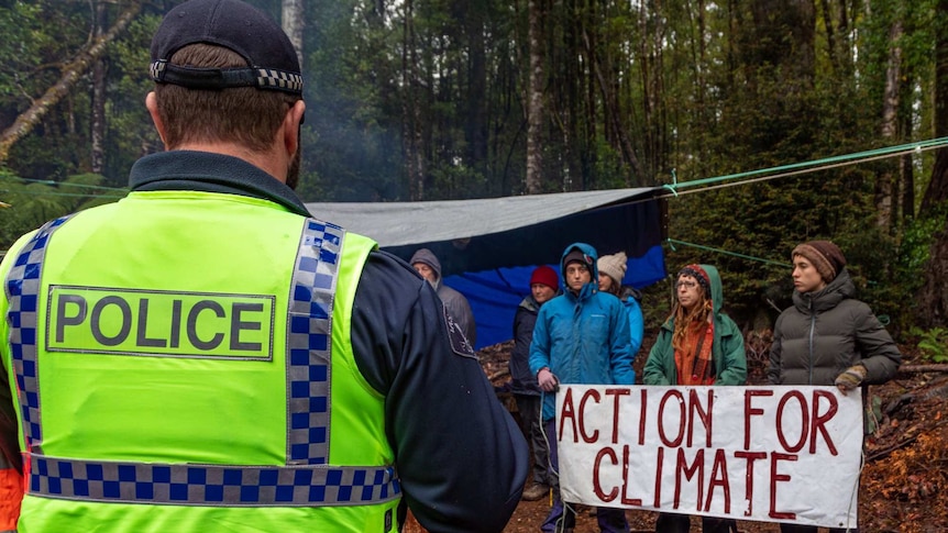 Tasmania Police officer looks at protesters at a site in the Tarkine forest, Tasmania, February 2020.
