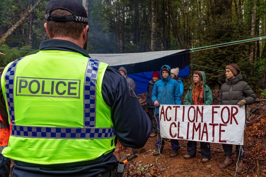 Ein tasmanischer Polizeibeamter betrachtet Demonstranten an einem Ort im Tarkine-Wald, Tasmanien, Februar 2020.