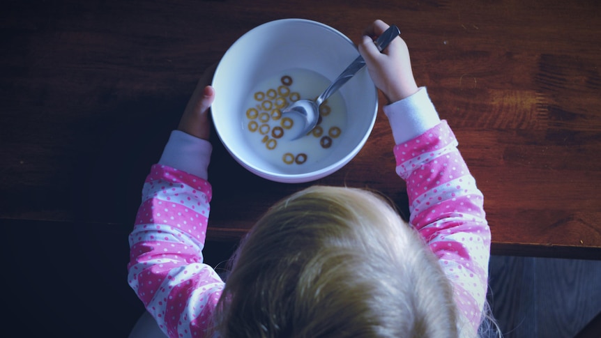 A bird's-eye view of a toddler eating a near empty bowl of cereal