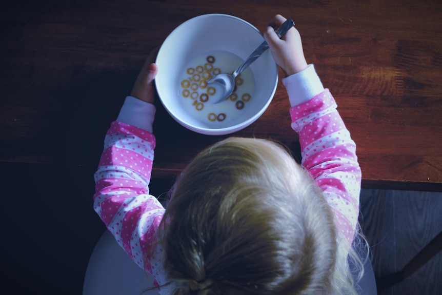 A birds eye view of a toddler eating a near empty bowl of cereal