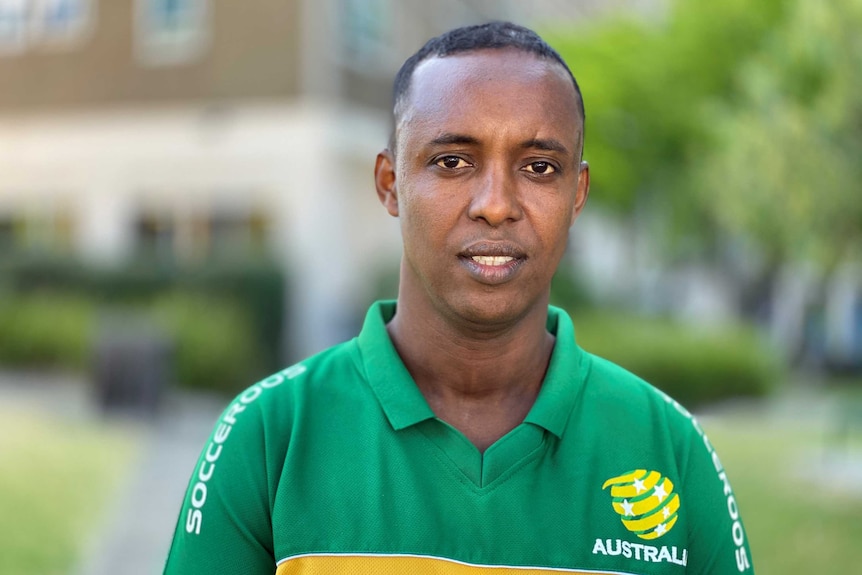 Awil Hussein wearing a green Socceroos shirt and looking into the camera.