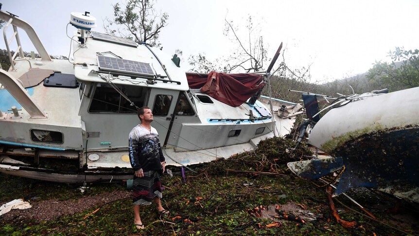 Bradley Mitchell inspects the damage to his uncle's boat after it smashed against the bank at Shute Harbour, Airlie Beach.