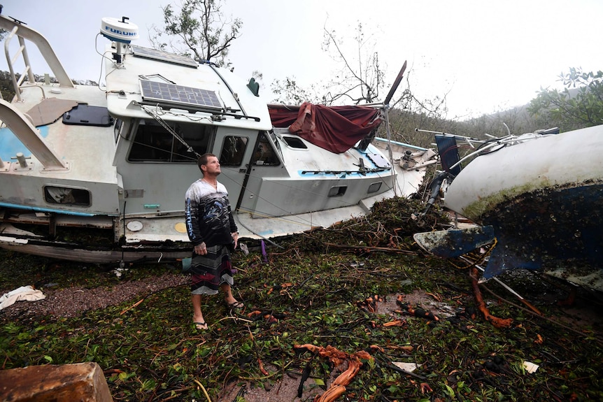 Bradley Mitchell inspects the damage to his uncle's boat after it smashed against the bank at Shute Harbour, Airlie Beach.