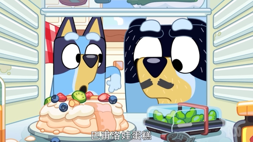 two cartoon blue heelers point to a pavlova and box of edamame in their fridge. a jar of vegemite is in the foreground.