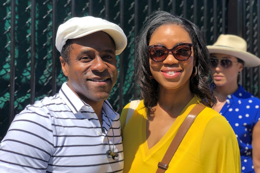 A couple smile for the camera at the gates of Wimbledon