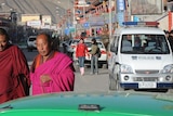 Tibetan monks walk in front of police cars in the town of Xiahe