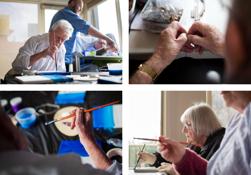 Elderly people paint at a craft session in an aged care facility