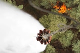 A helicopter drops water over a forest fire