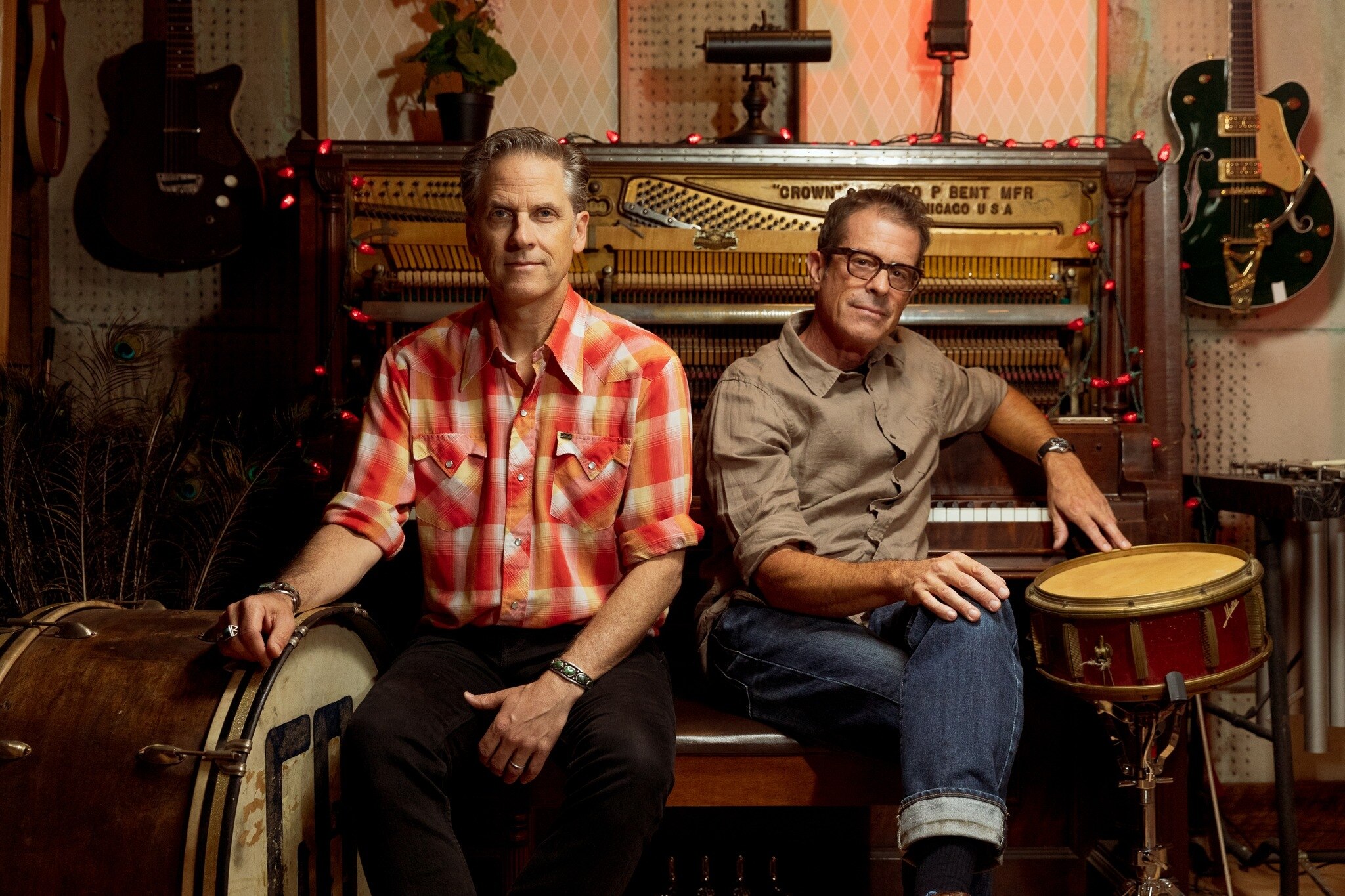 Calexico's Joey Burns and John Convertino pose in a studio in front of an open piano