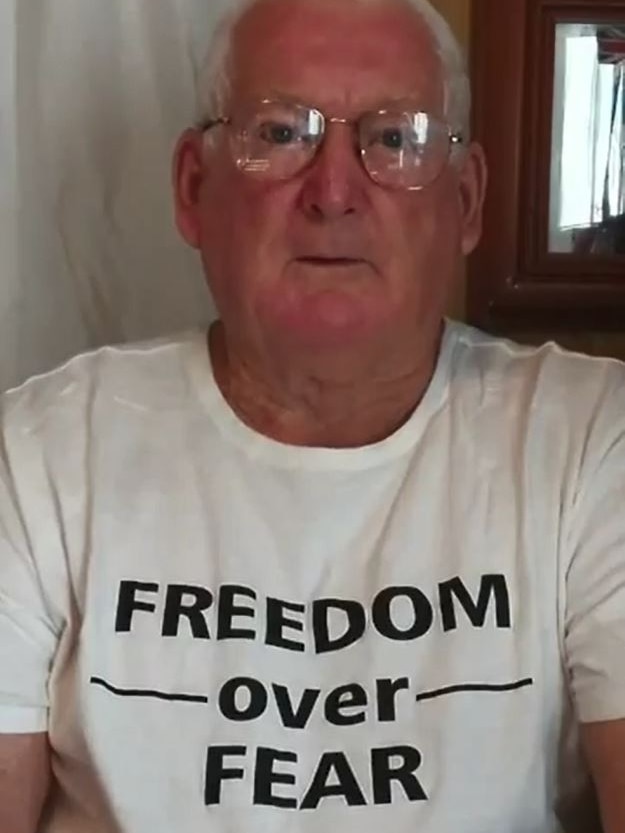 A man in glasses wearing a white tshirt with 'freedom over fear' in black letters, looks at the camera.