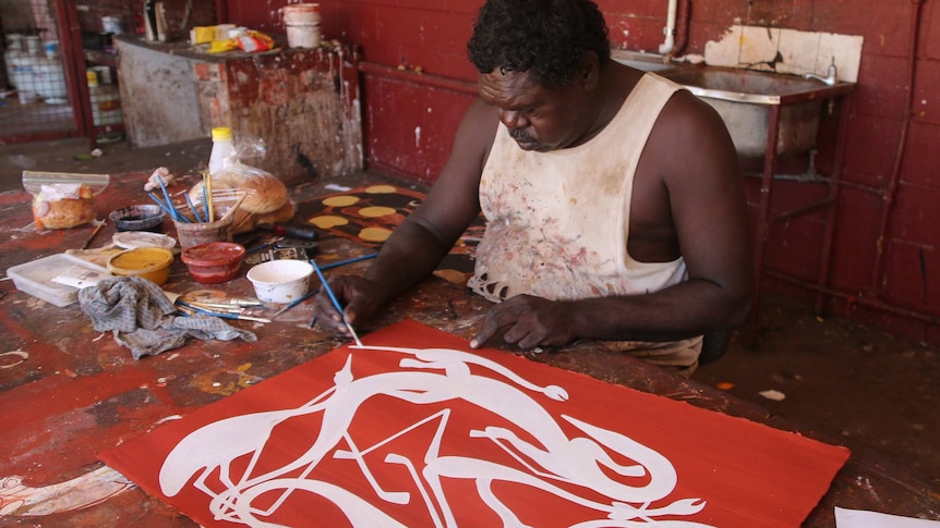 Artist and co-manager Gabriel Maralngurra paints in traditional ochre paints.