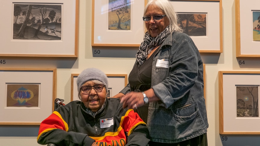 Two women in front of children's drawings at the Carrolup exhibition at Curtin University