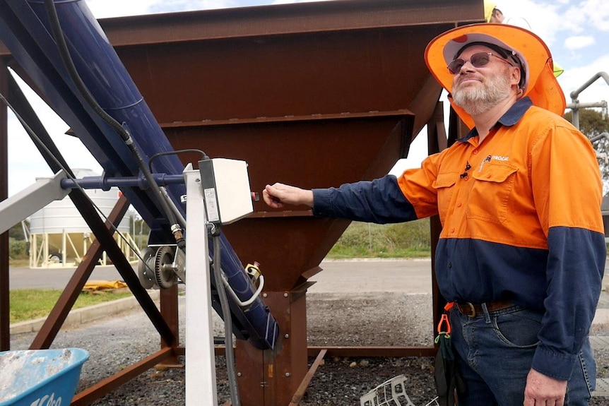 A man in industrial high-vis clothig operating heavy machinery