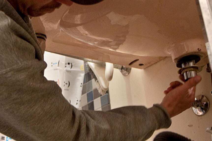A plumber fixes a sink.