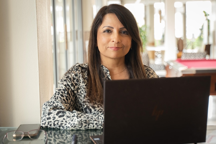 Farzila Farhad using a black laptop and looking at the camera.