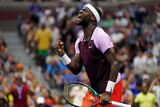 A headband-wearing tennis player closes his eyes, pumps his fist and shouts in celebration during a match.