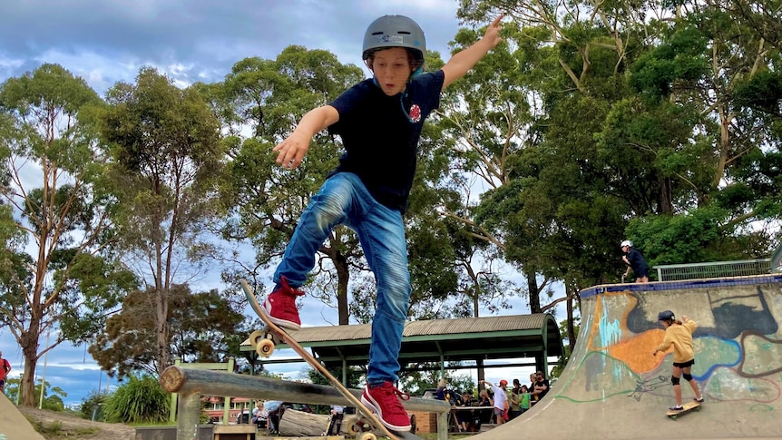 A young boy skating in a skate park with a helmet.
