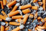 A smoker's ashtray filled with cigarette butts and ash.