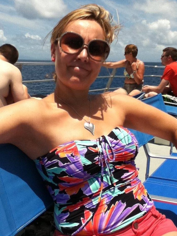 Kylie Blackwood, a woman with blonde hair, smiles at the camera while sitting on a boat.