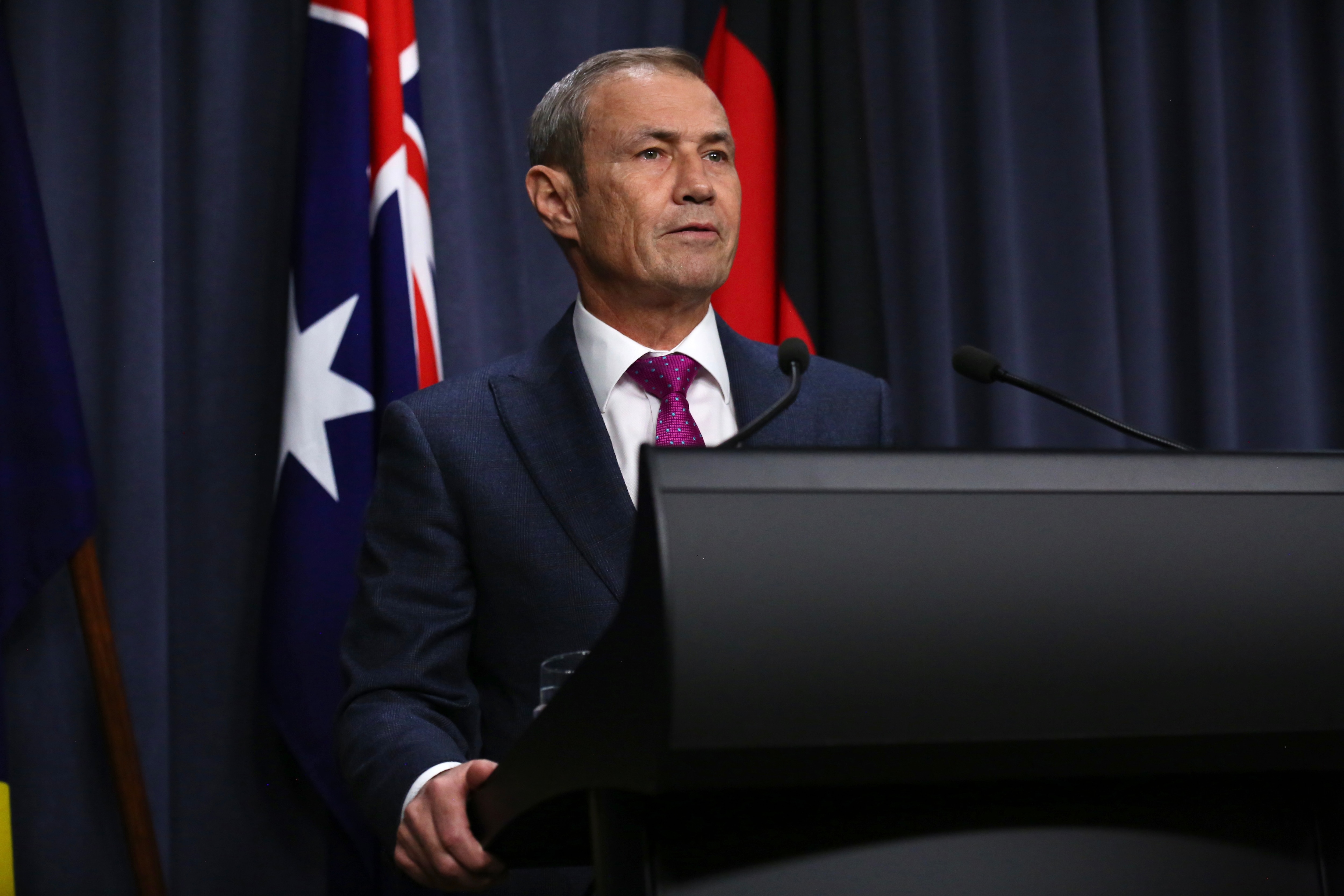 A man in a suit speaks at a lectern 