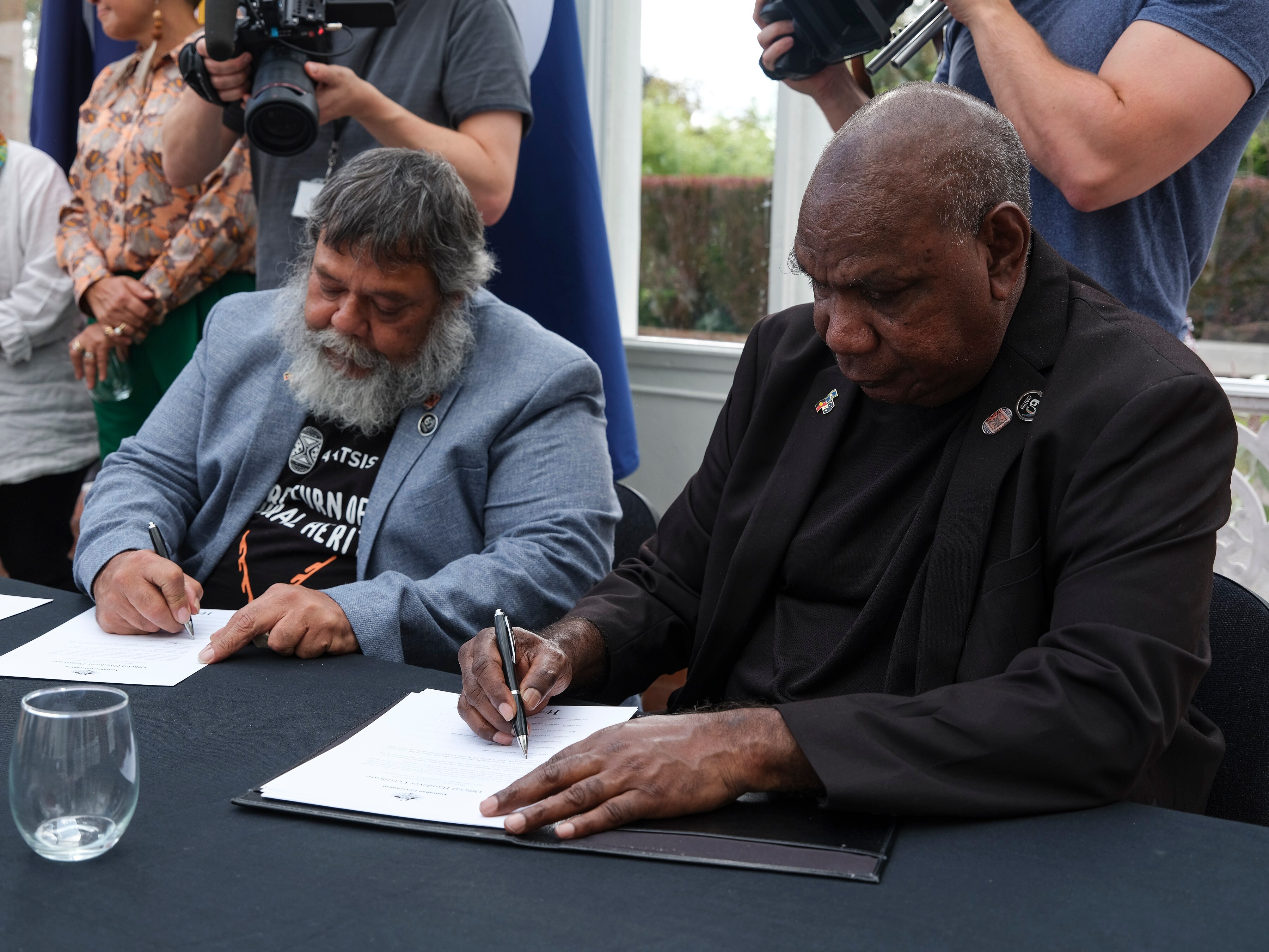 Warumungu elders sitting at table and signing papers at the Horniman Museum and Gardens in London. 