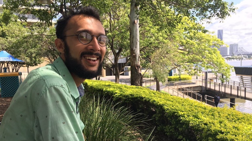 a man with glasses and dark hair smiling 