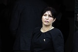 Roberta Williams dressed in black stares into the camera lense at the funeral of Carl Williams