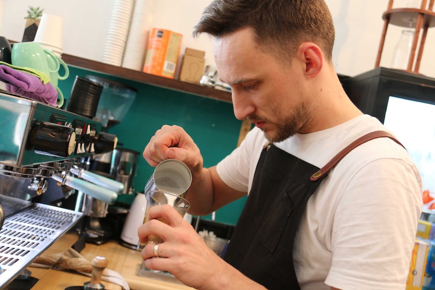 A barista behind the coffee machine.