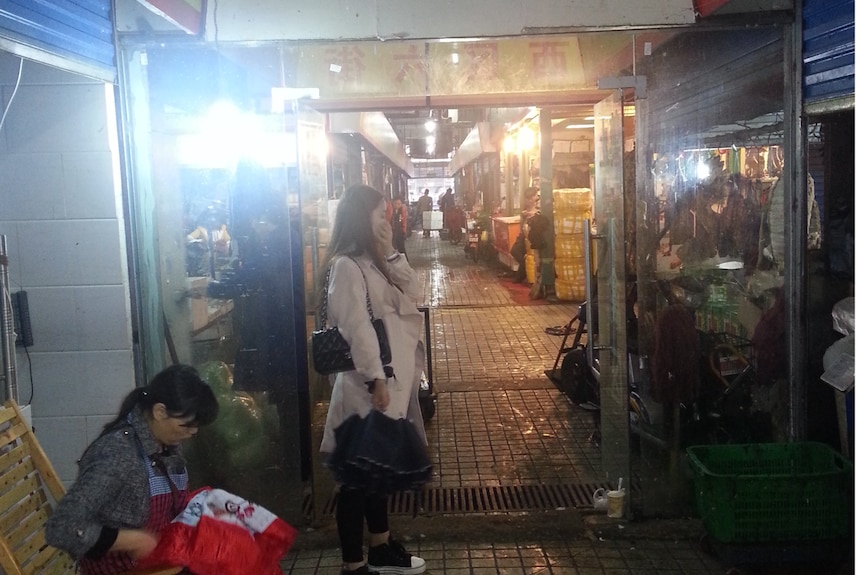 Dark and dirty entrance to a market with signs in Chinese.